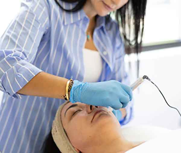 A skincare professional performs a microneedling treatment using a serum-infused device to rejuvenate skin, enhance texture, and boost natural collagen.