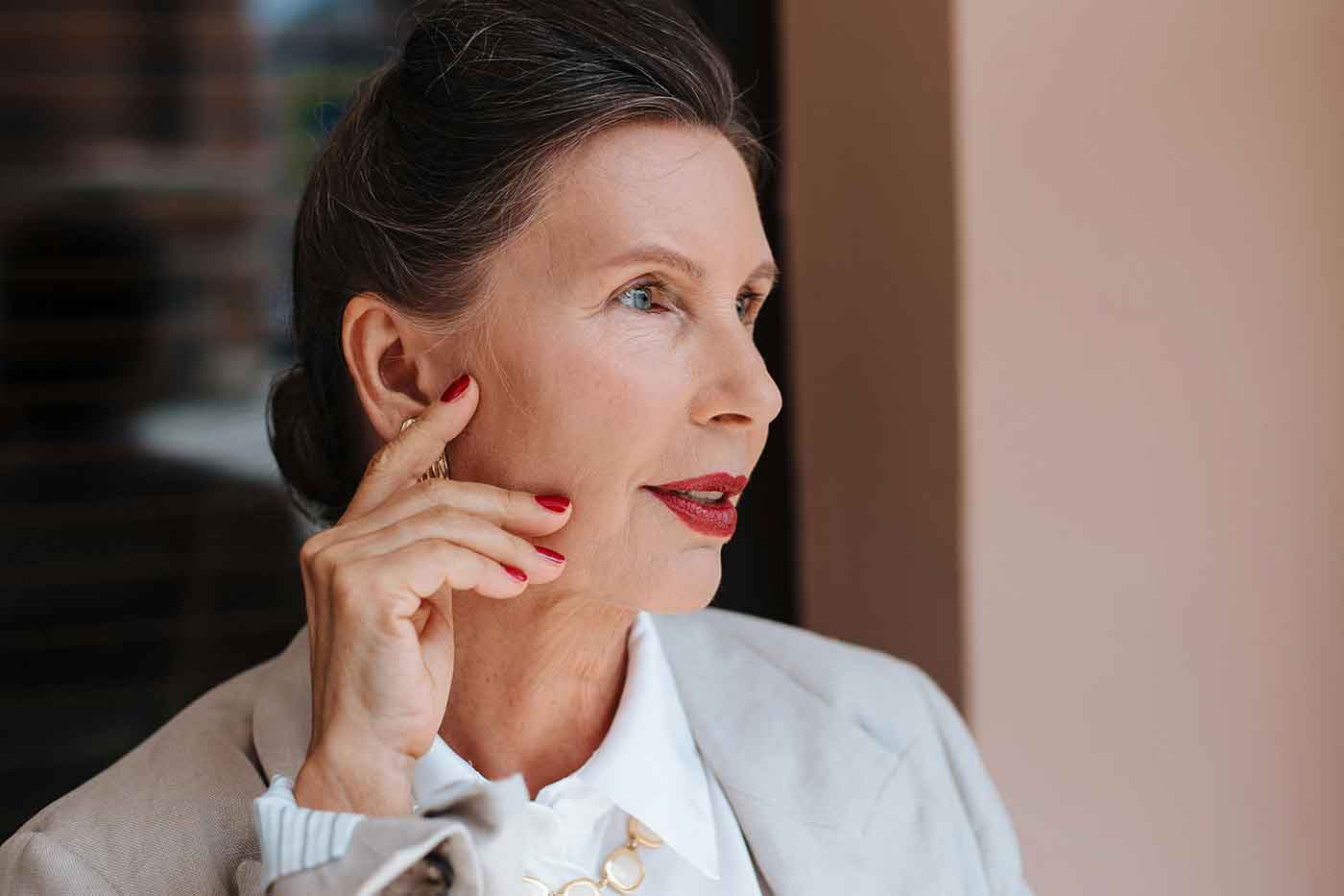 A confident, mature woman with radiant, healthy skin, showcasing the visible benefits of regular anti-aging facials and a consistent skincare routine.