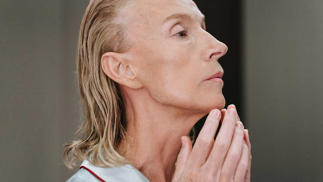 Mature woman examining her face at Skin&Tonic in Raleigh, contemplating her next facial spa treatment to enhance skin health.