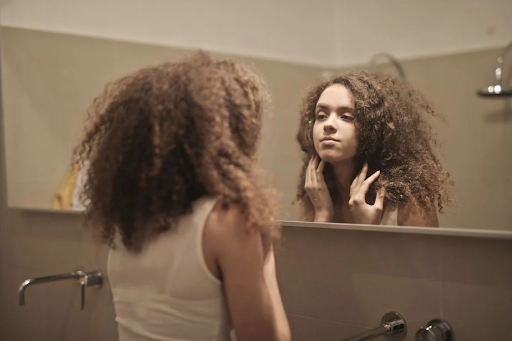 Woman examines her skin in a mirror, considering which Biologique Recherche P50 version is right for her skin type.
