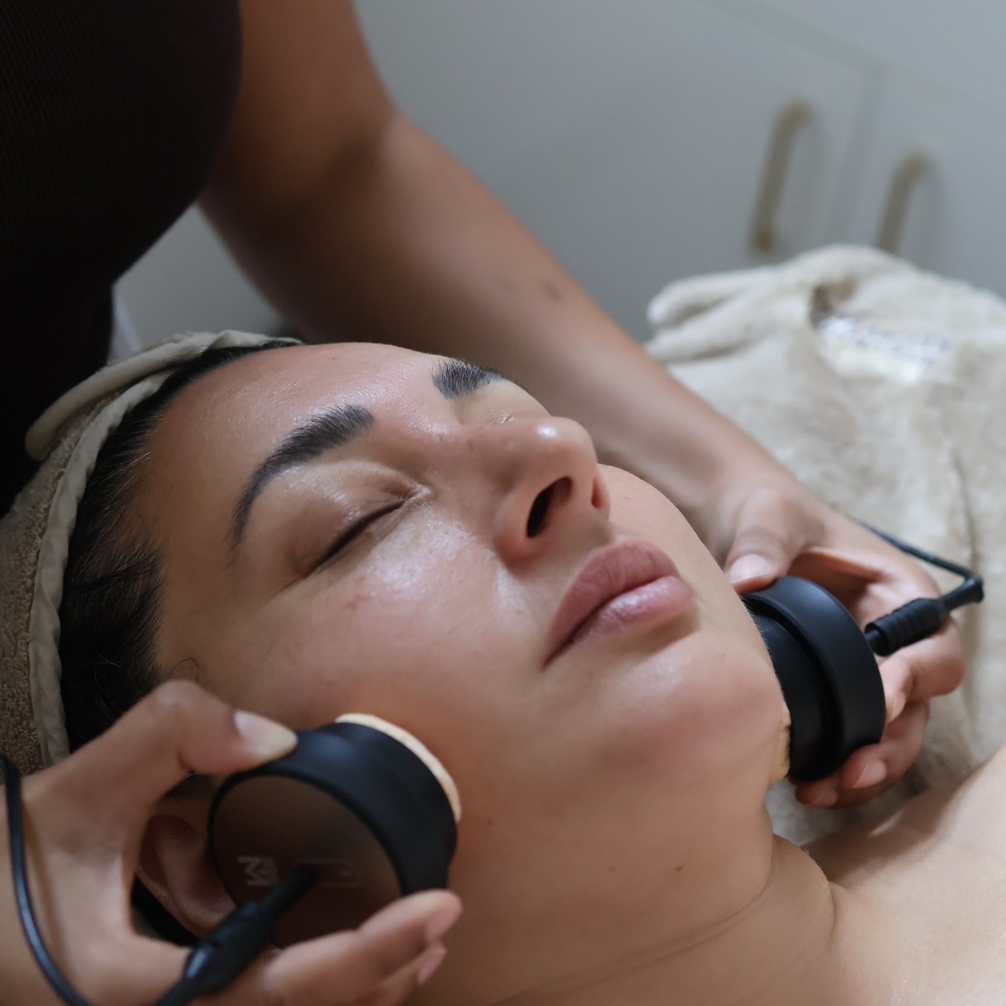 Person receiving a Bio Visage facial treatment with electronic devices on a neutral background